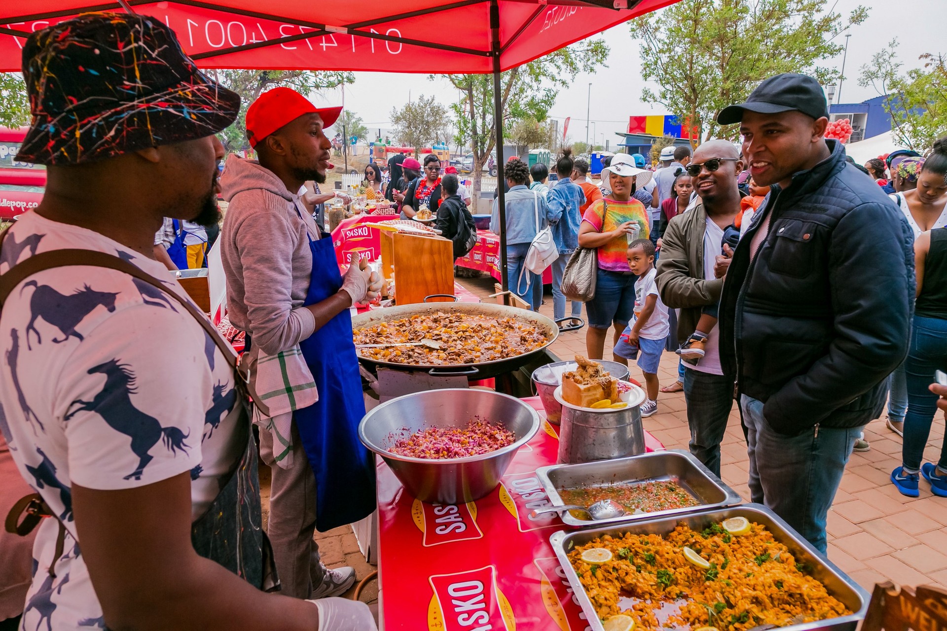 Diverse African vendors cooking and serving various bread based street food at outdoor festival